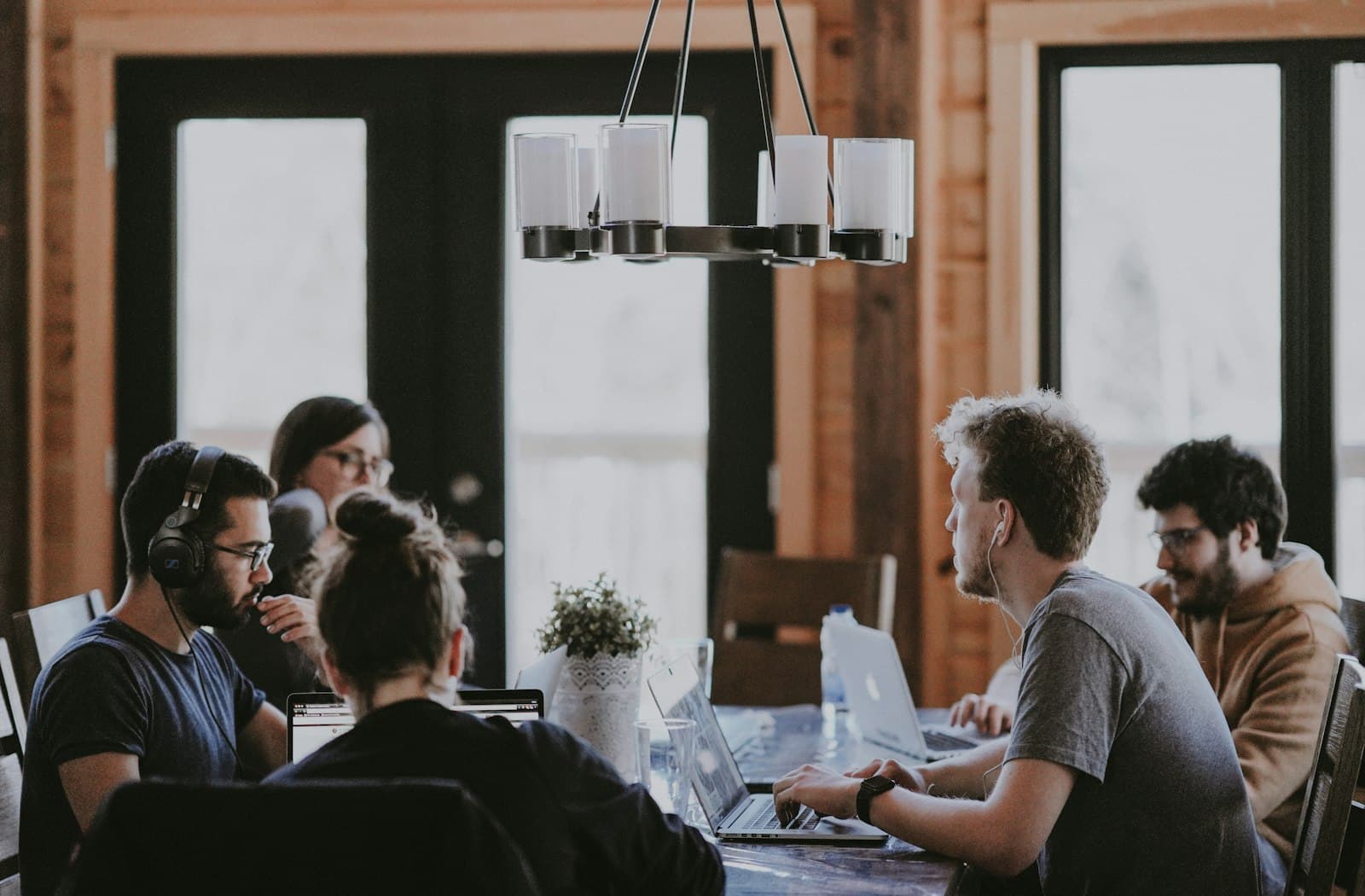 A small team collaborating at a shared table, some wearing headsets